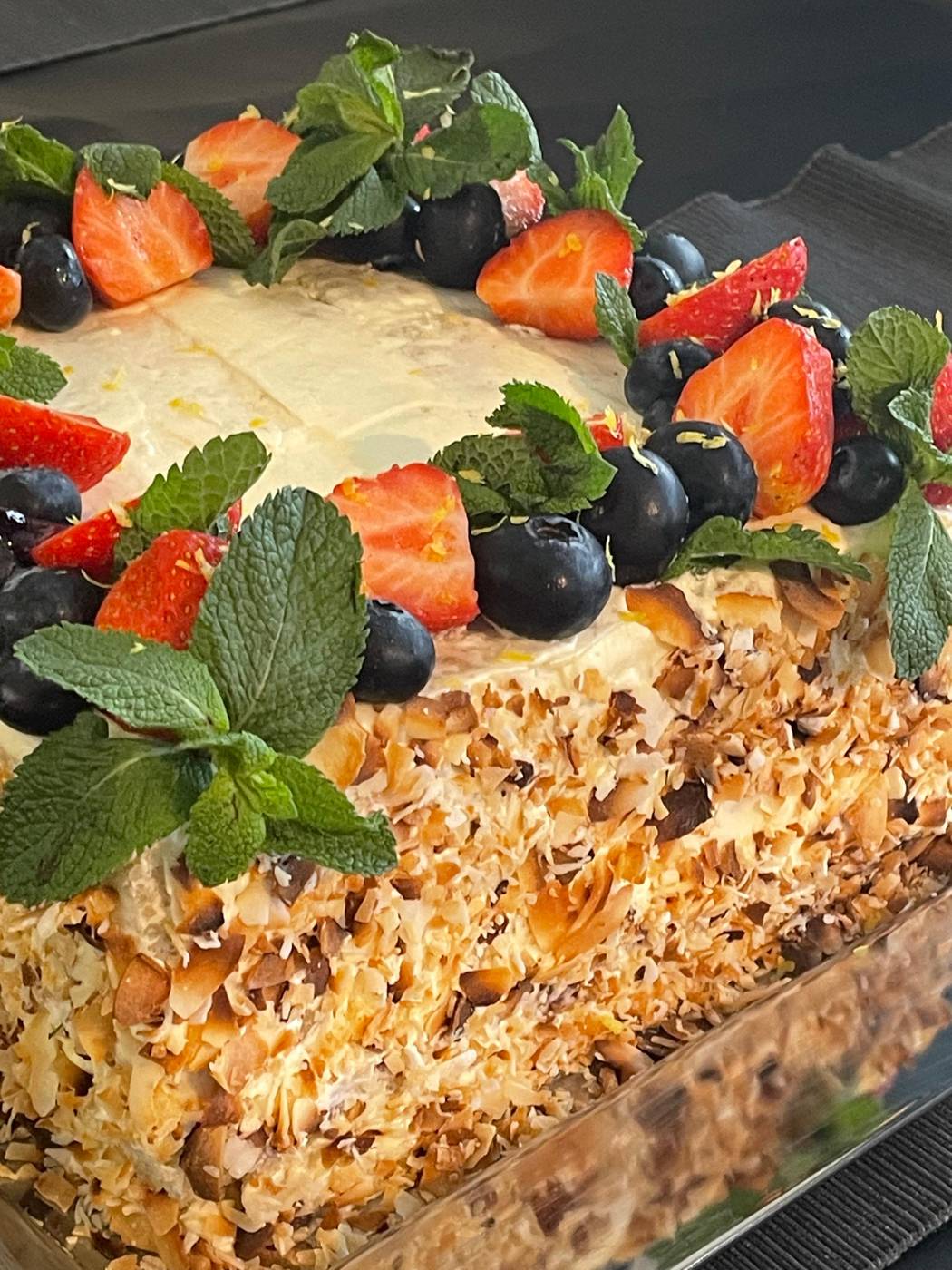 Layered cake topped with strawberries, blueberries and mint