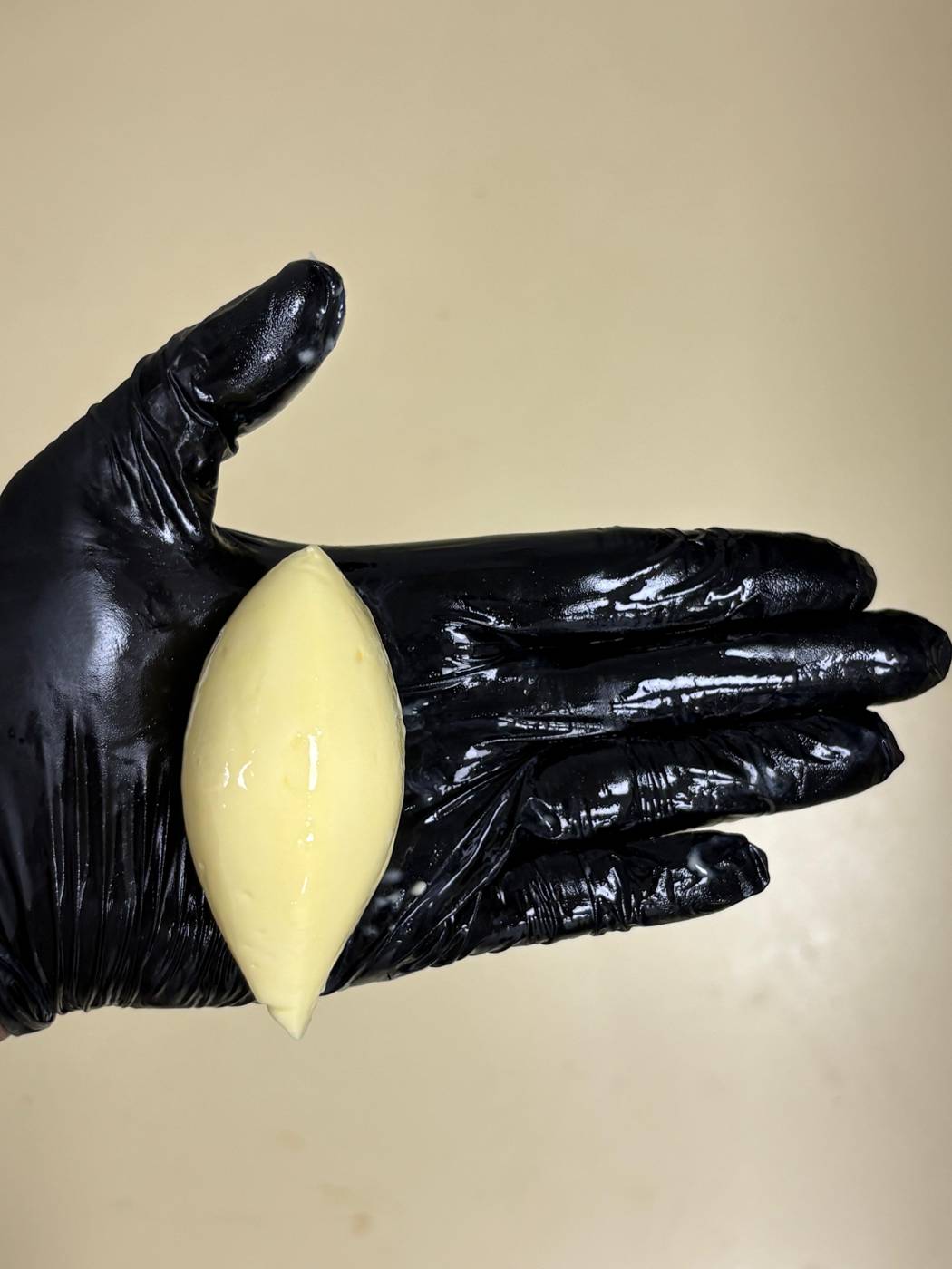 A quenelle held in a black-gloved hand